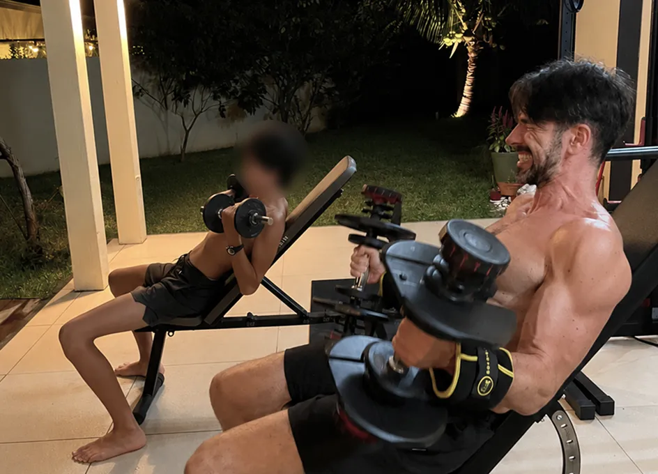 Benoît et son fils s’entraînant ensemble aux haltères, le soir dans le jardin
