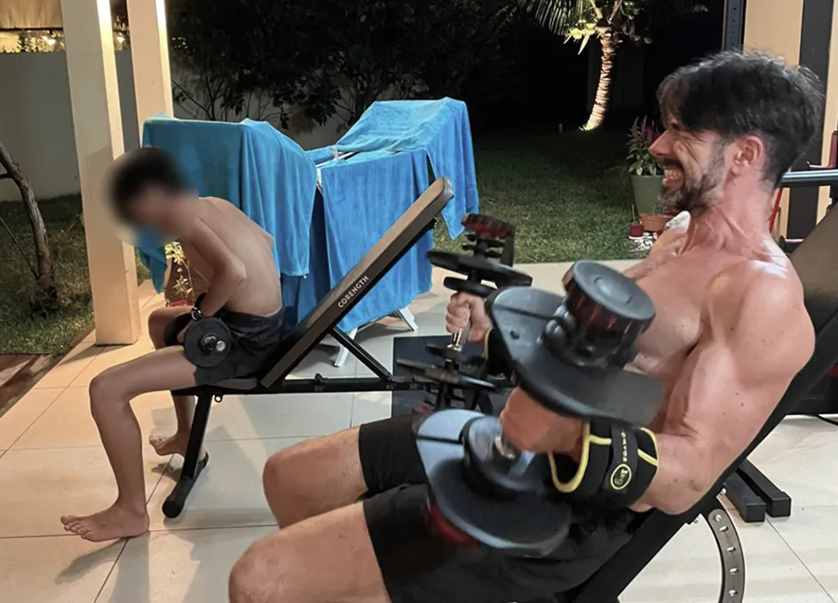 Benoît et son fils s’entraînant ensemble aux haltères, le soir dans le jardin